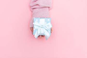 White gift box with red bow in the children's hands on pink background