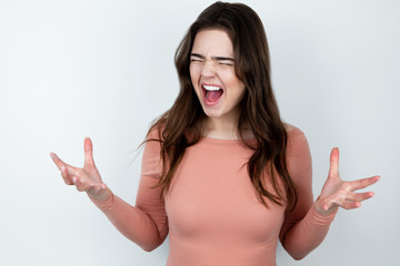 young beautiful brunette woman standing on isolated white background looking angry ,splash of...