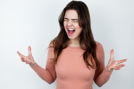 young beautiful brunette woman standing on isolated white background looking angry ,splash of emotions