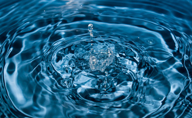 water drop splash in a glass blue colored. Fresh liquid concept. Close up.