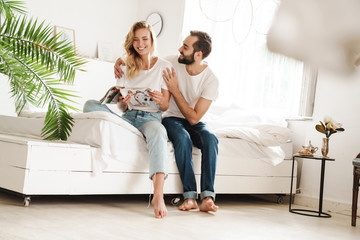 Couple indoors at home on bed reading magazine.
