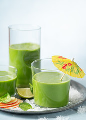 Green smoothie in glass with organic ingredients, vegetables on a light background with copy space. Selective focus. Food and drink, healthy dieting, nutrition, alkaline, vegan, vegetarian concept.