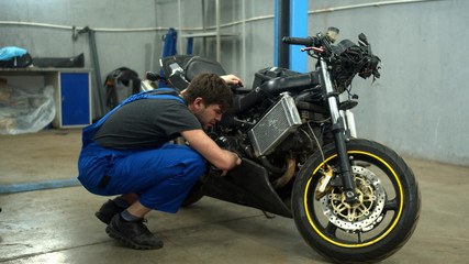 Fototapeta na wymiar Mechanic examines a motorcycle in auto repair shop