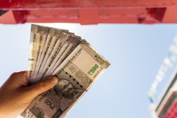 Hands holding new series Indian five hundred rupee notes with building of north India in...