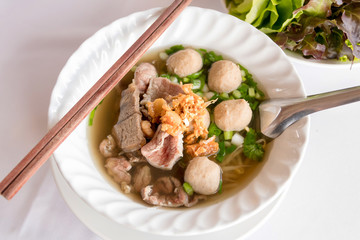 Bowl of beef noodle soup with meatballs and sliced beef; garlic cracklings with lard on top.