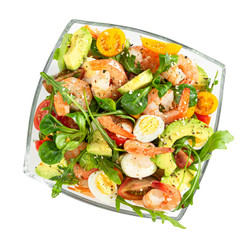 Salad with avocado, shrimp and arugula in glass bowl isolated on white