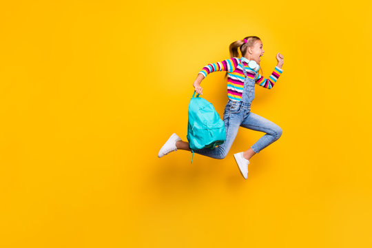 Full body profile side photo crazy schoolchild jump run school discounts hold blue bag rucksack wear striped sweater denim jeans suspenders overalls isolated bright shine yellow color background