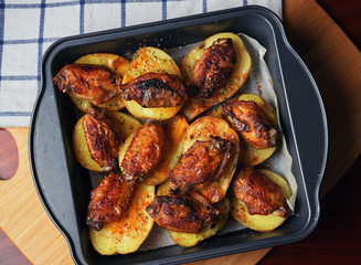 Baked chicken wings and potatoes in the tray