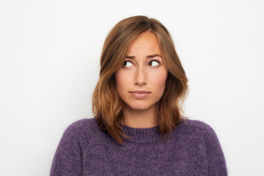 Portrait Of A Young Woman Skeptical And Thinking On White Background