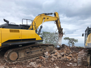 Obraz premium Excavator and hydrohammer during road construction on the rocky soils