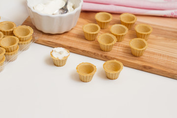 Tartlets with custard or cottage cheese. Empty tartlets or pie on a white table. Food lay flat. The view from the top. The concept of preparing food for the holiday table.