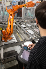 Man programming robot in automotive industrial, professional programmer, industry concept