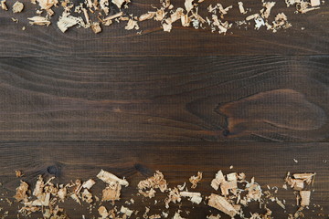 light wood shavings on dark wooden background flat lay with copy space