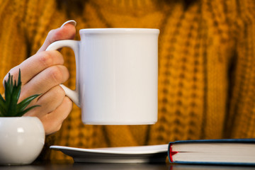 hand holding cup of coffee on wooden table