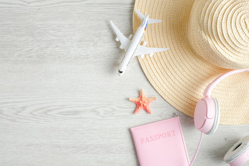 Trendy female travel accessories on wooden background. Top view beach hat, airplane model, passport...