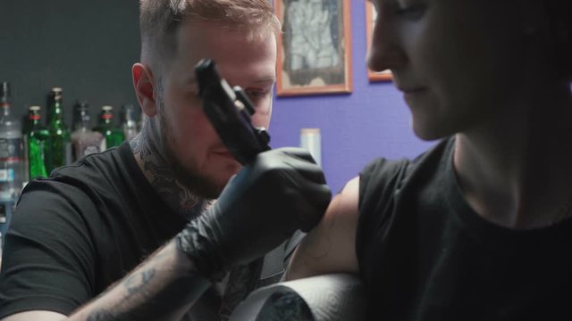 Footage of young tattooer getting tattoo of snake in salon