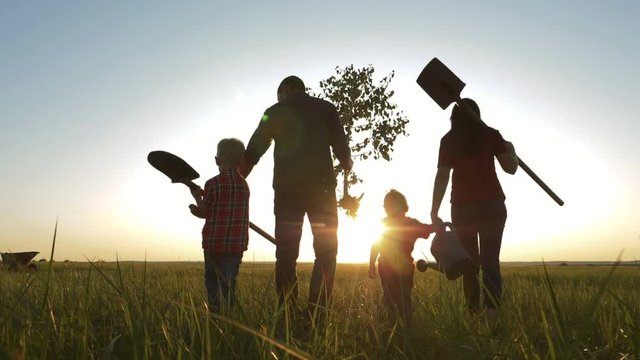 agriculture red neck farming happy family walking agriculture of farmers a silhouette concept slow motion video. mom dad son and daughter walk go children happy family plant and water the tree
