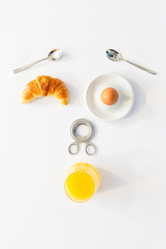 Fun breakfast concept with abstract astonished human face made of breakfast items on white background.