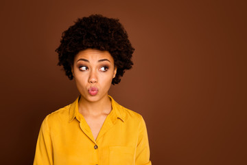 Closeup photo of beautiful pretty dark skin curly lady looking shy side empty space avoid handsome guy eyes sending him air kiss wear yellow shirt isolated brown color background