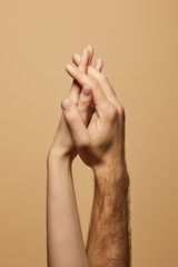 partial view of man and woman holding hands isolated on beige