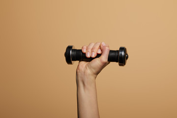 Fototapeta na wymiar cropped view of woman holding dumbbell isolated on beige