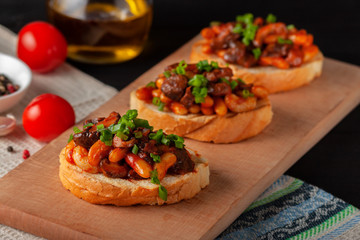 Bruschetta with beans and mushrooms on a wooden board
