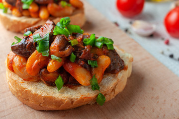 Bruschetta with beans and mushrooms on a wooden board