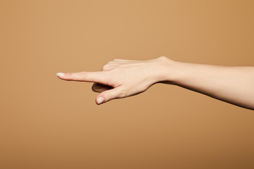 cropped view of woman pointing with finger isolated on beige