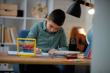 Cute little boy doing homework. Child learning foe school. 