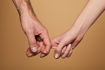 cropped view of man and woman holding fingers isolated on beige