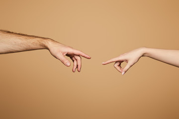 cropped view of man and woman reaching each other with fingers isolated on beige