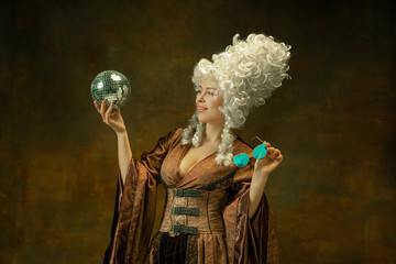 Ready for party. Portrait of medieval young woman in vintage clothing with discoball, eyewear on...