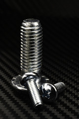 glänzende schrauben in verschiedenen größen auf untergrund aus carbon 