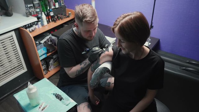 Video of young master getting tattoo of snake in salon, top view