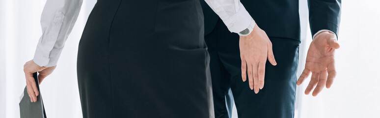 panoramic shot of secretary touching leg of businessman in office