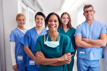 Portrait Of Laughing Multi-Cultural Medical Team Standing In Hospital Corridor - Powered by Adobe