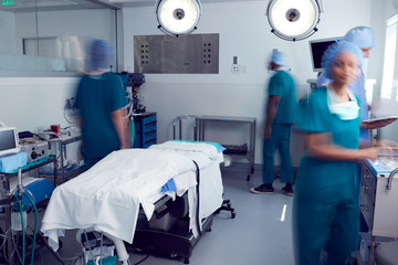 Motion Blur Shot Of Surgical Team Wearing Scrubs In Busy Hospital Operating Theater