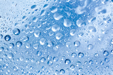 Backdrop glass covered with drops of water. Photo closeup with white and light blue background