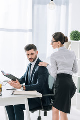 secretary touching shoulder of handsome businessman in office
