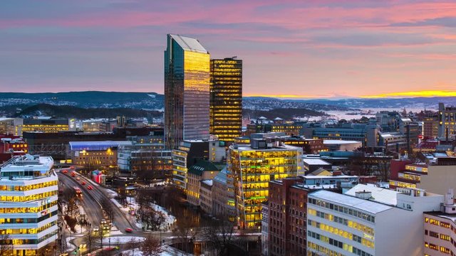 Oslo, Norway. A night view of Sentrum area of Oslo, Norway, with modern and historical buildings and car traffic. Sunset colorful sky in winter with snow, time-lapse with car traffic, panning video