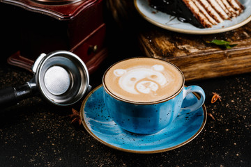 Delicious fresh morning cappuccino coffee in a ceramic blue cup on black background