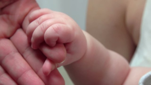 Sweet Little fingers of a baby hold adult hand of an adult parent