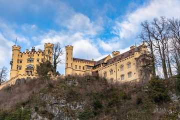 Fototapeta na wymiar Beautiful view of the famous Hohenschwangau Castle on a sunny day in winter, with blue sky and cloud background, Schwangau, Bavaria, Germany
