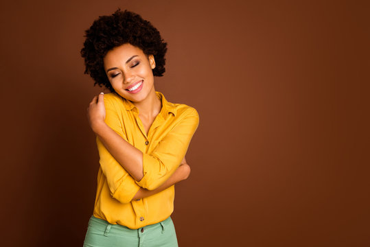 Photo of charming beautiful dark skin lady holding shoulders eyes closed enjoy love herself nice blouse clothes wear yellow shirt green trousers isolated brown color background