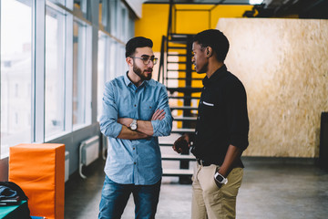 Calm relaxed multiethnic students having conversation in corridor of modern building of university