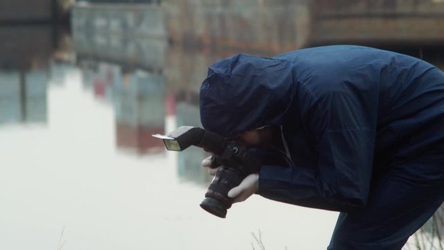 Forensic detective taking photos of dead person, crime scene closeup in harbor