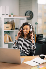 Young businesswoman listening music. Beautiful african woman in office. 