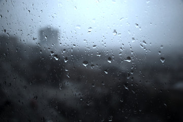 Drops of rain on the window close-up. View of the city through the window. Gray view from the window.