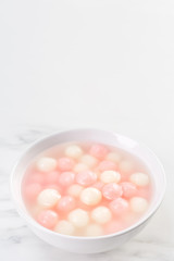 Tang yuan, tangyuan, delicious red and white rice dumpling balls in a small bowl. Asian traditional festive food for Chinese Winter Solstice Festival, close up.
