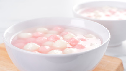 Obraz na płótnie Canvas Tang yuan, tangyuan, delicious red and white rice dumpling balls in a small bowl. Asian traditional festive food for Chinese Winter Solstice Festival, close up.